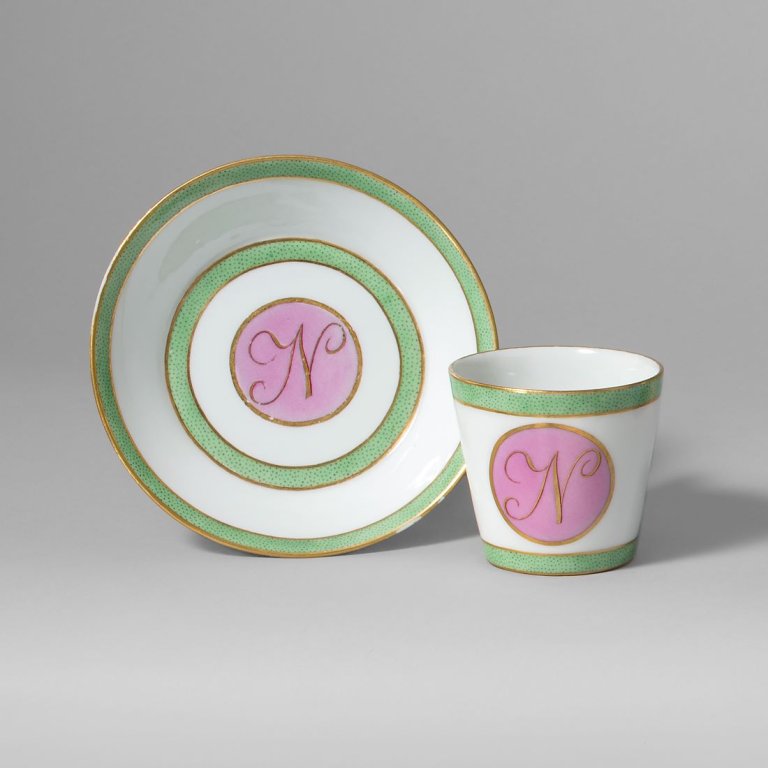 Auf diesem Bild ist das folgende Kunstwerk zu sehen:  KPM Königliche Porzellan-Manufaktur Berlin. Tasse Antikglatt, Henkel à la grecque mit blauem Fond und der Darstellung der „Marchande de Cupidons“. Um 1805.