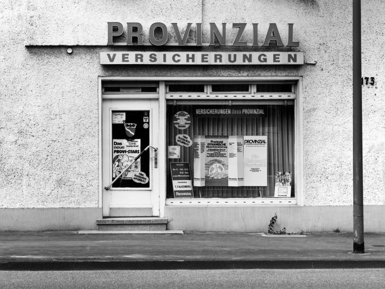 Auf diesem Bild ist das folgende Kunstwerk zu sehen: Tata Ronkholz. Versicherung, Leverkusen-Schlehbusch, Neubergerstr. 173, aus der Serie „Läden“. 1979.