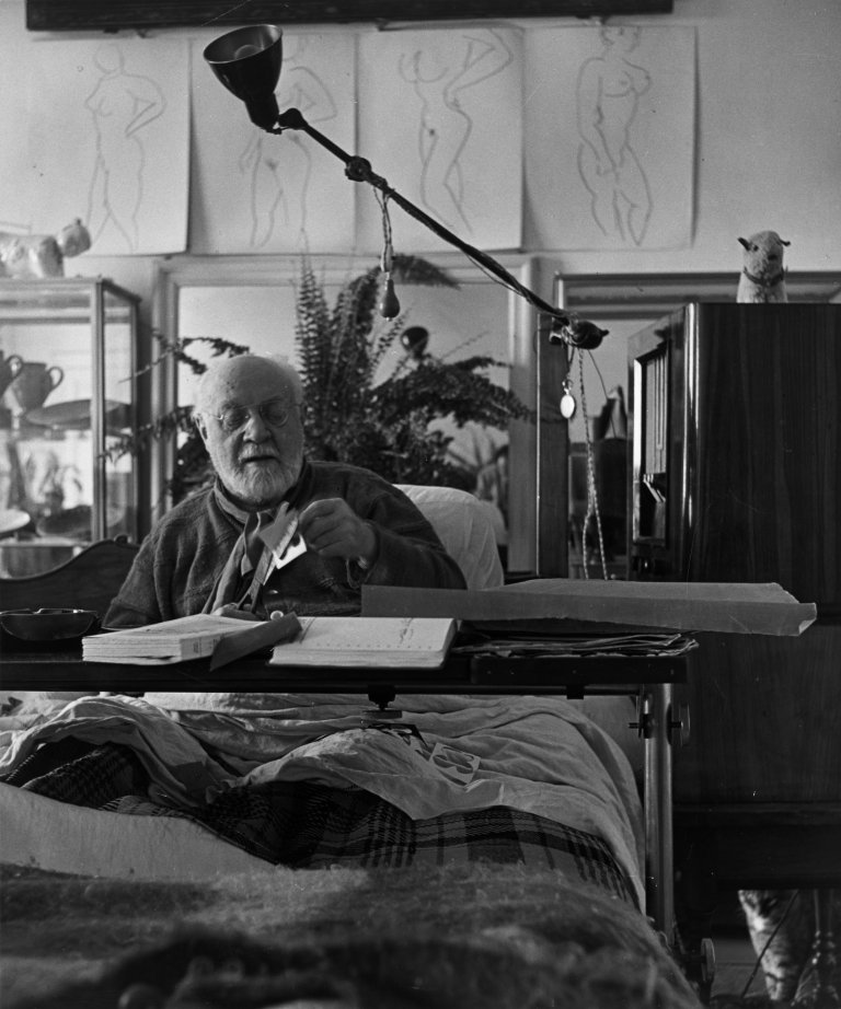 Auf diesem Bild ist das folgende Kunstwerk zu sehen: Philippe Halsman. Matisse working on a cut-out under his Chinese calligraphy panel at Hôtel Régina, Nice, March. 1951.