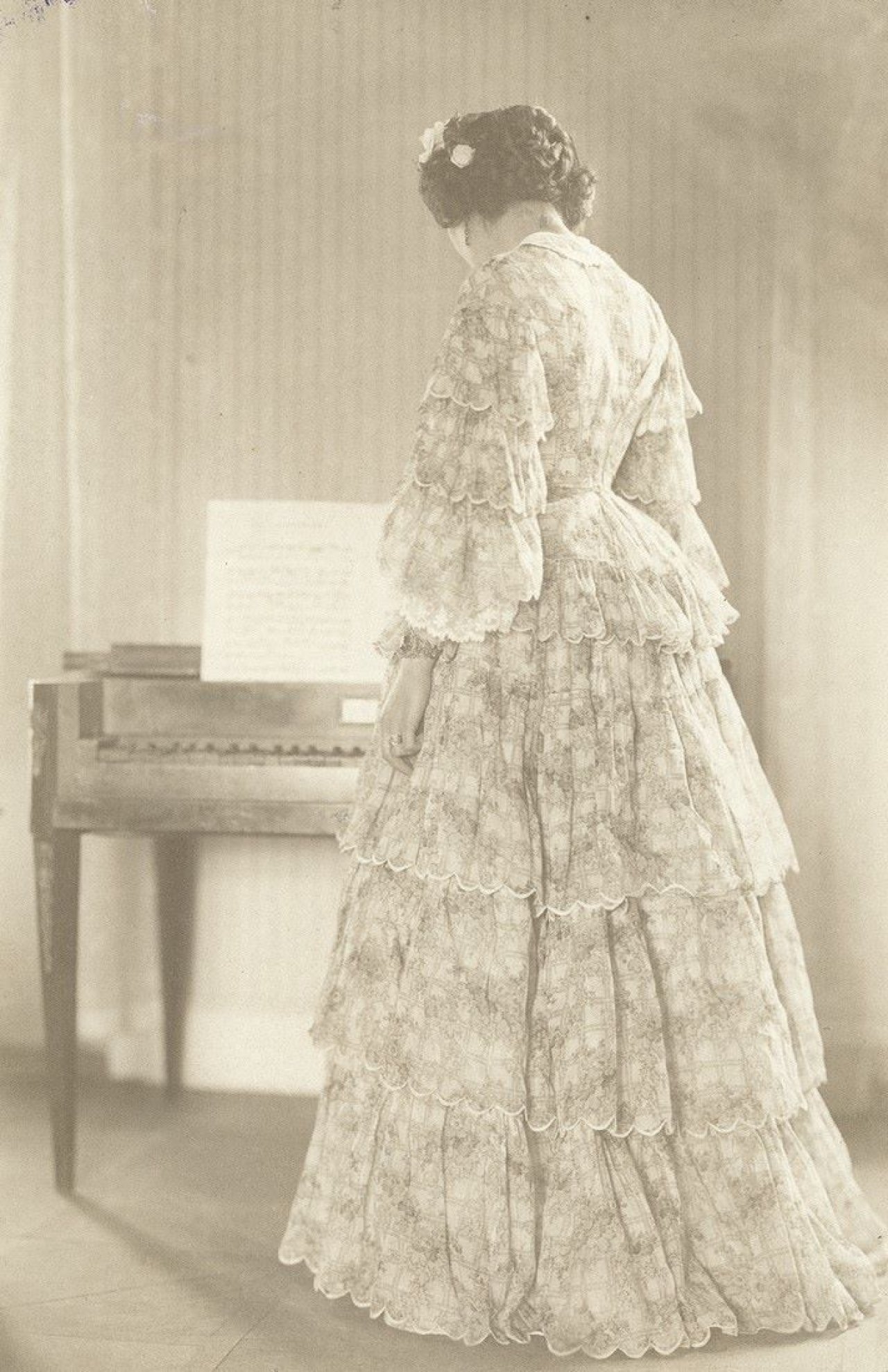 Auf diesem Bild ist das folgende Kunstwerk zu sehen: Hugo Erfurth. „Helene Erfurth“ am Klavier (Kostümstudien). 1909.