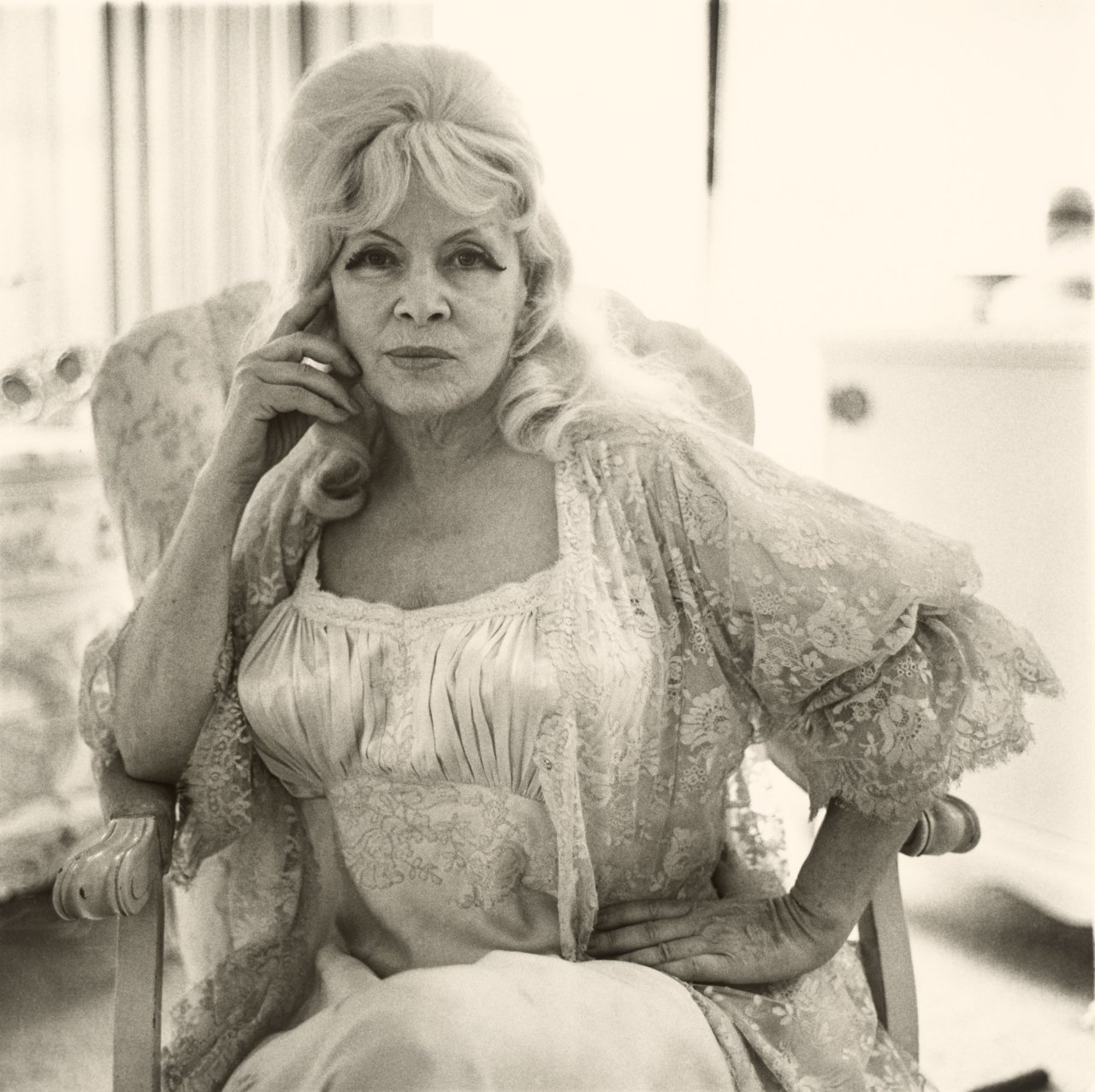 Auf diesem Bild ist das folgende Kunstwerk zu sehen: Diane Arbus. Mae West in a chair at home, Santa Monica, Cal.[ifornia]. 1965.