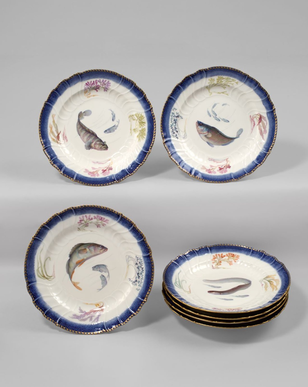 Auf diesem Bild ist das folgende Kunstwerk zu sehen:  KPM Königliche Porzellan-Manufaktur Berlin. Sieben Teller Neuozier mit Fisch-Motiven. Um 1912.