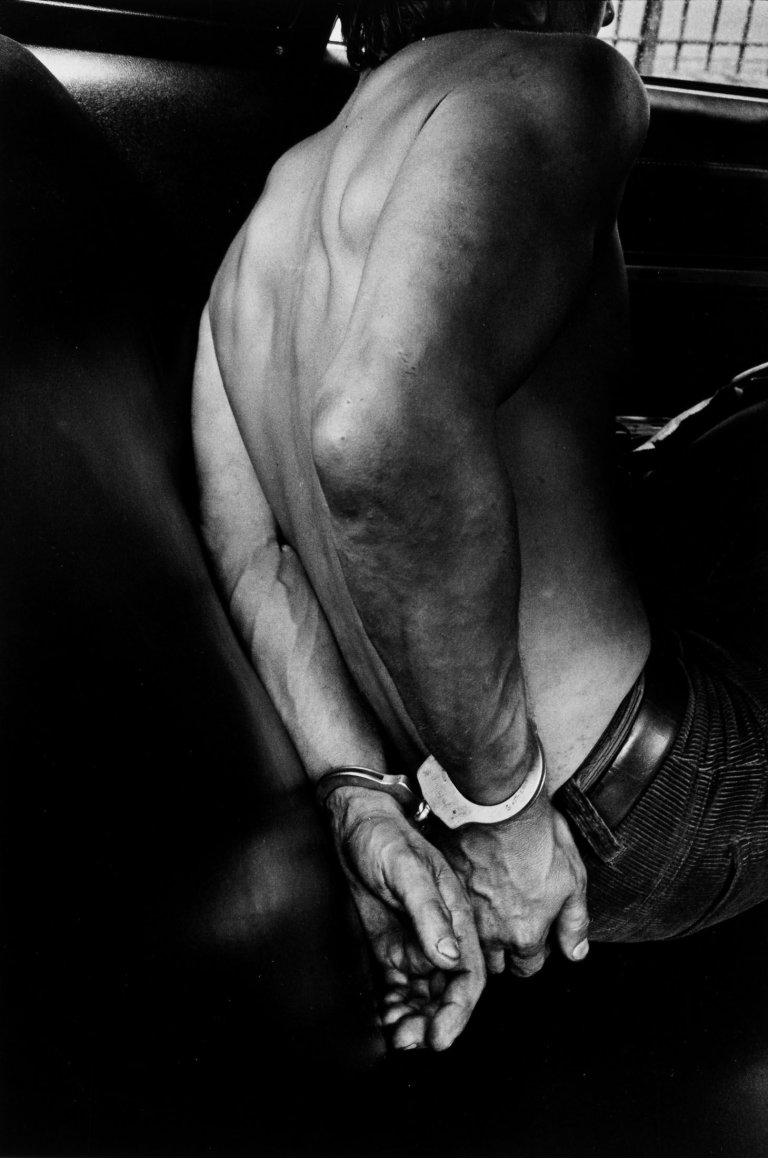 Auf diesem Bild ist das folgende Kunstwerk zu sehen: Leonard Freed. A Man taken into Custody in a Police car, New York City. 1978.