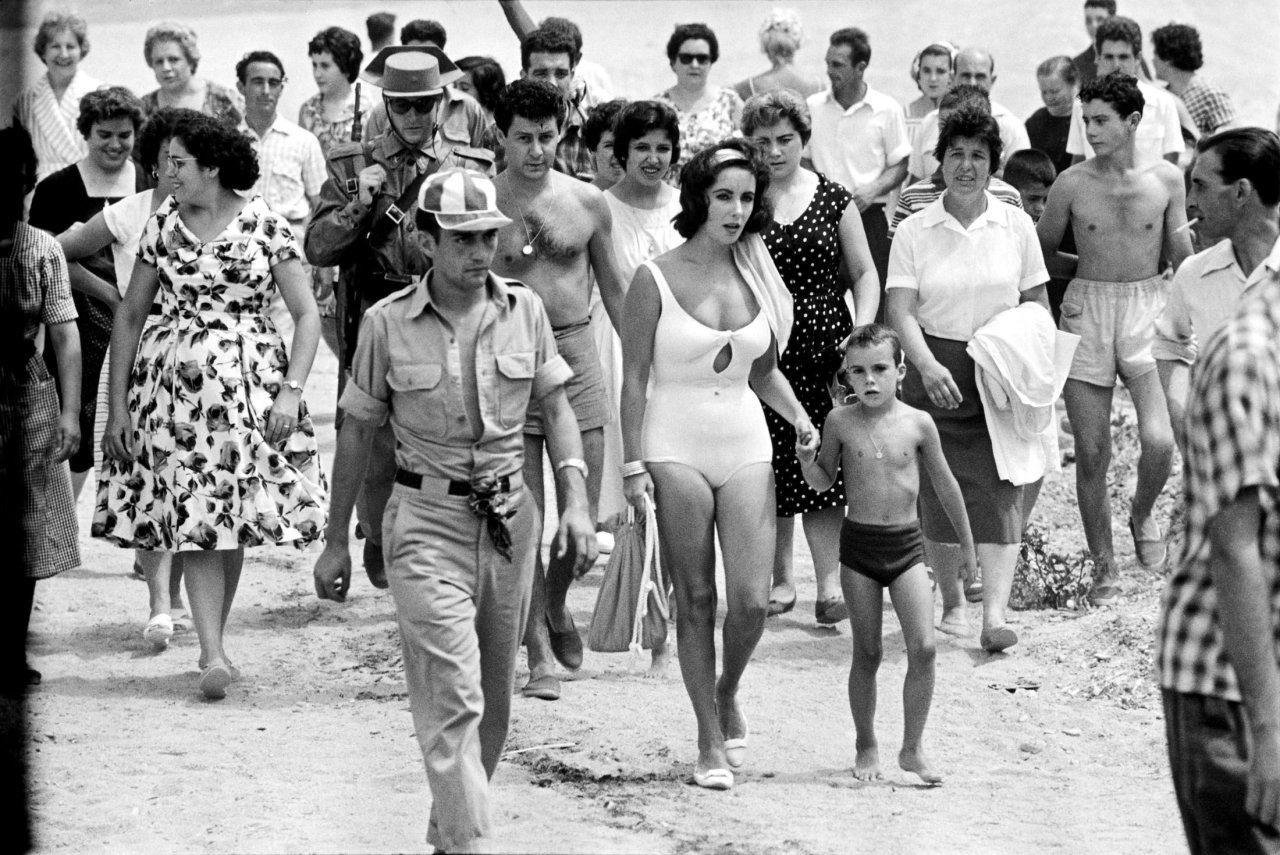 Auf diesem Bild ist das folgende Kunstwerk zu sehen: Burt Glinn. Elizabeth Taylor with her son Christopher while shooting the film „Suddenly Last Summer“, S‘Agaró, Spanien. 1959.