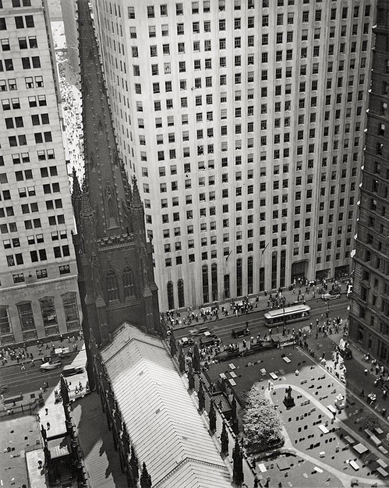 Auf diesem Bild ist das folgende Kunstwerk zu sehen: Berenice Abbott. Trinity Churchyard looking down Wall Street, New York City. Um 1938.