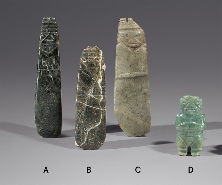 Auf diesem Bild ist das folgende Kunstwerk zu sehen:  Präkolumbisch, Kultur der Guanacaste. Jadeanhänger – Länglicher Axtgott, unten gerundet mit stilisiertem Gesicht und keilförmiger Nase, die Augen gebohrt, Hände über den Bauch gelegt (Linea Vieja). 600–900 n. Chr..