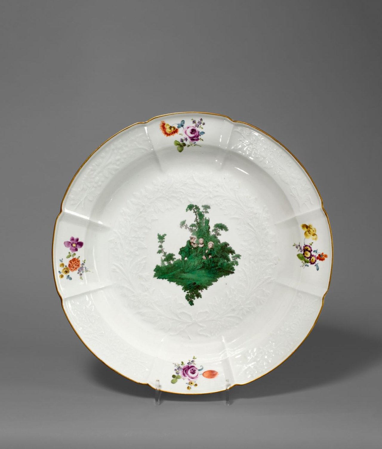 Auf diesem Bild ist das folgende Kunstwerk zu sehen:  Porzellanmanufaktur Meissen. Große Schüssel mit Gotzkowsky-Relief und moosgrüner Watteauszene, Blumendekor und goldenem Rand. Um 1750.