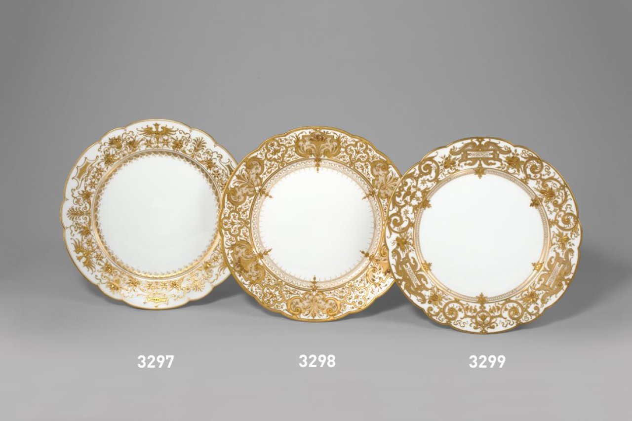 Auf diesem Bild ist das folgende Kunstwerk zu sehen:  KPM Königliche Porzellan-Manufaktur Berlin. Zierteller Augustaform mit Kartuschen und Obstkörben in Reliefgold. Um 1900.