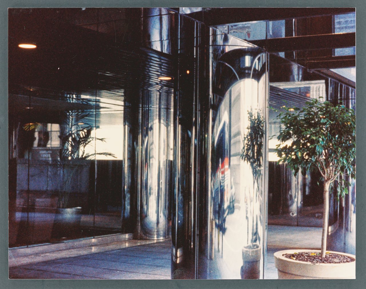 Auf diesem Bild ist das folgende Kunstwerk zu sehen: Dan Graham (d.i. Daniel Harry Ginsberg). „Anamorphic stainless steel column - NYC office bldg.“. 2010.