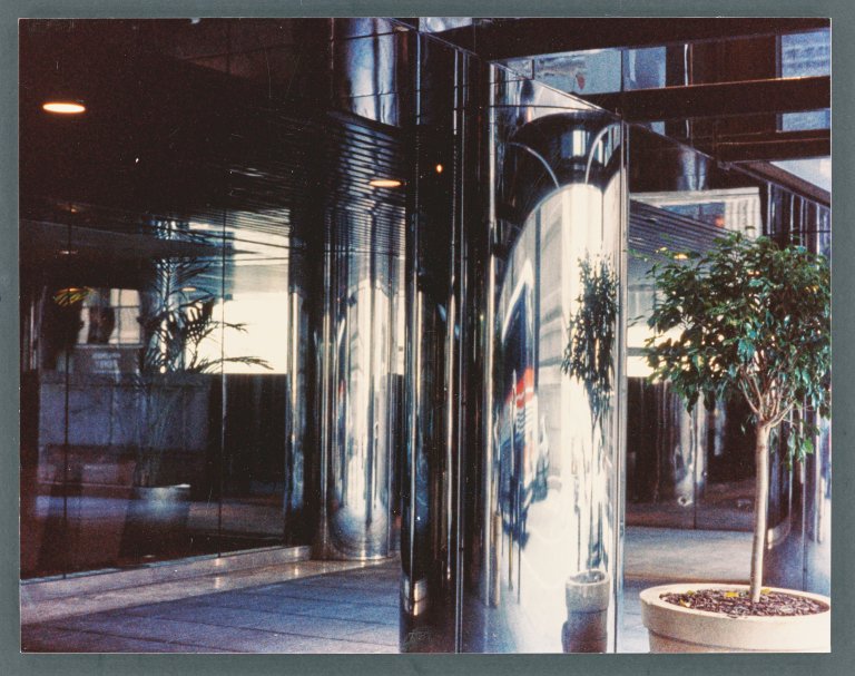 Auf diesem Bild ist das folgende Kunstwerk zu sehen: Dan Graham (d.i. Daniel Harry Ginsberg). „Anamorphic stainless steel column - NYC office bldg.“. 2010.