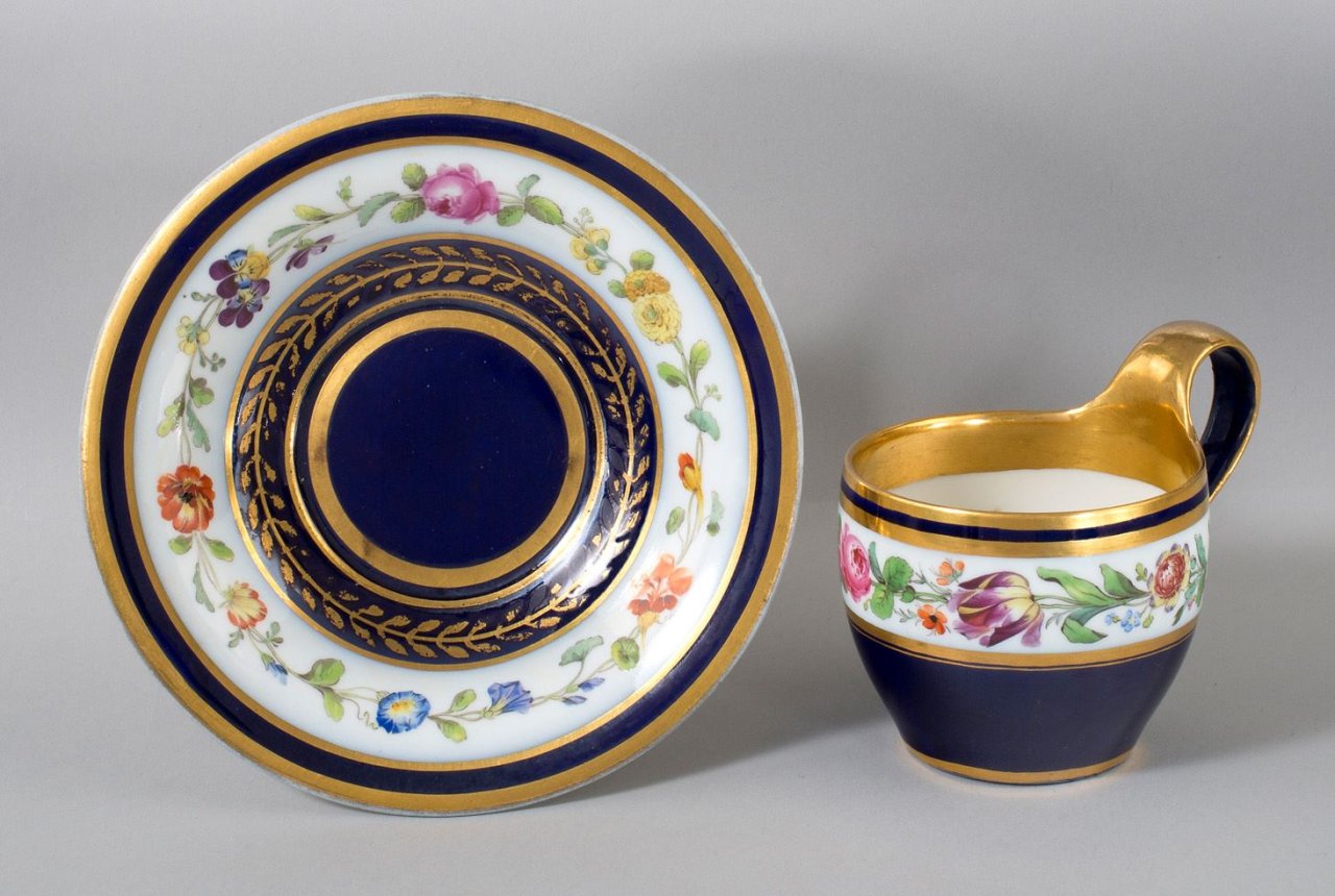 Auf diesem Bild ist das folgende Kunstwerk zu sehen:  Porzellanmanufaktur Meissen. Kobaltblaue Tasse (Campaner Form) und Untertasse mit Blumenband. Um 1820.