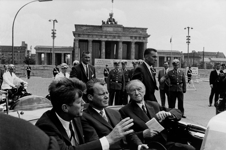 Auf diesem Bild ist das folgende Kunstwerk zu sehen: Will McBride. „John F. Kennedy, Willy Brandt, Konrad Adenauer vorm Brandenburger Tor, Berlin“. 1963.