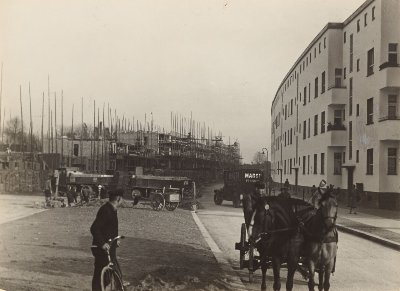Auf diesem Bild ist das folgende Kunstwerk zu sehen: Sasha und Cami Stone. Berlin Weissensee. Neue Siedlung, Fassadenfront Buschallee, Bauarbeiten Laubenkolonie. Architekt: Bruno Taut. Aus der Serie: Das Neue Berlin. 1929.