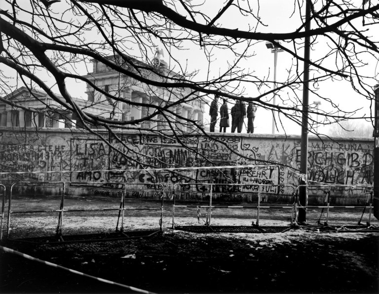 Auf diesem Bild ist das folgende Kunstwerk zu sehen: Thomas Lüttge. „Vier auf der Mauer“, Berlin, Brandenburger Tor, Dezember. 1989.