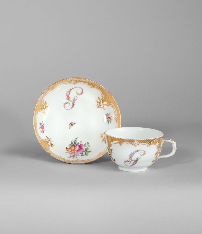 Auf diesem Bild ist das folgende Kunstwerk zu sehen:  KPM Königliche Porzellan-Manufaktur Berlin. Tasse und Untertasse Neuzierat mit farbigen Blumenbuchstaben G und Goldschuppenmosaik. Um 1780.