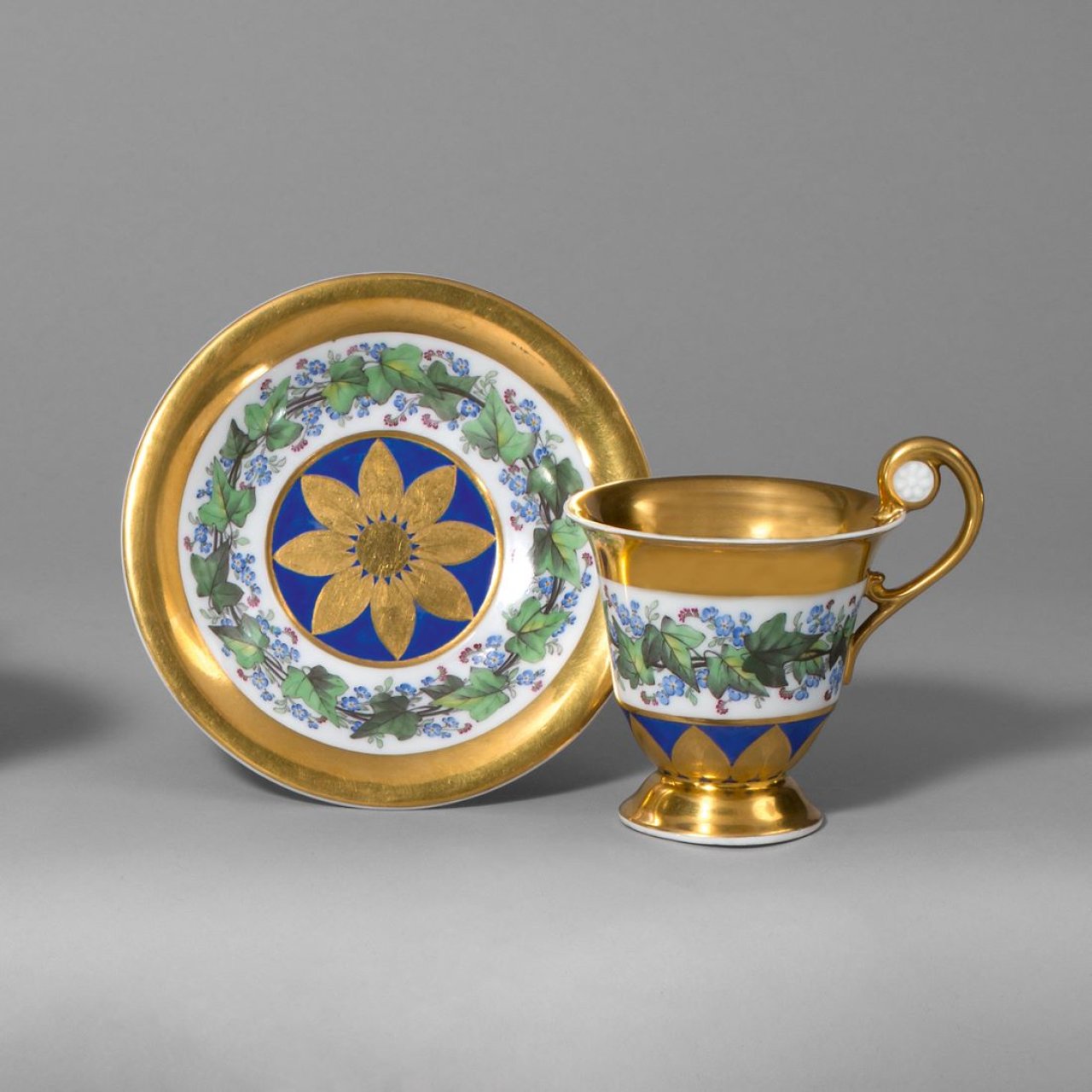 Auf diesem Bild ist das folgende Kunstwerk zu sehen:  KPM Königliche Porzellan-Manufaktur Berlin. Tasse in Glockenbecherform mit Rosettenhenkeln, Efeuband und reicher Vergoldung. Um 1815/20.