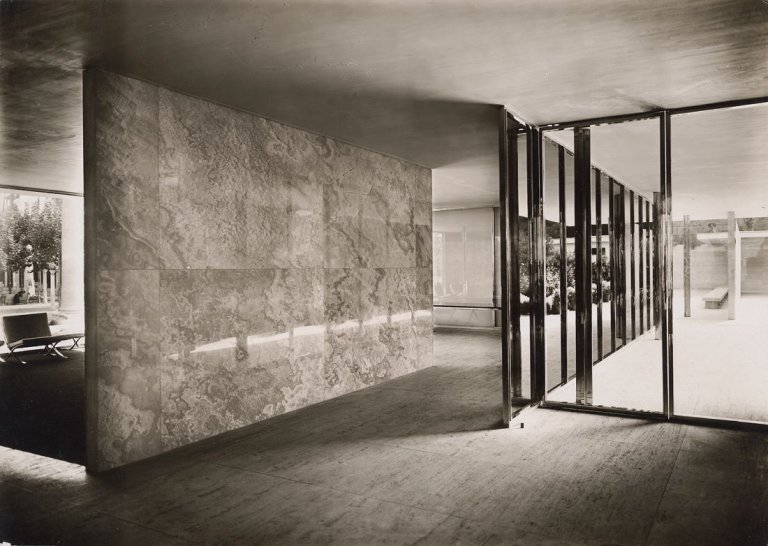 Auf diesem Bild ist das folgende Kunstwerk zu sehen: Ludwig Mies van der Rohe. Barcelona Pavillon, Ansicht des Nebeneingangs mit Blick auf die Onyxwand und den Nebenanbau. 1929.