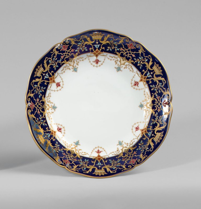 Auf diesem Bild ist das folgende Kunstwerk zu sehen:  KPM Königliche Porzellan-Manufaktur Berlin. Zierteller Englischglatt mit Grafenkronen in Reliefgold und Emailemalerei auf blauem Fond. Um 1900/10.