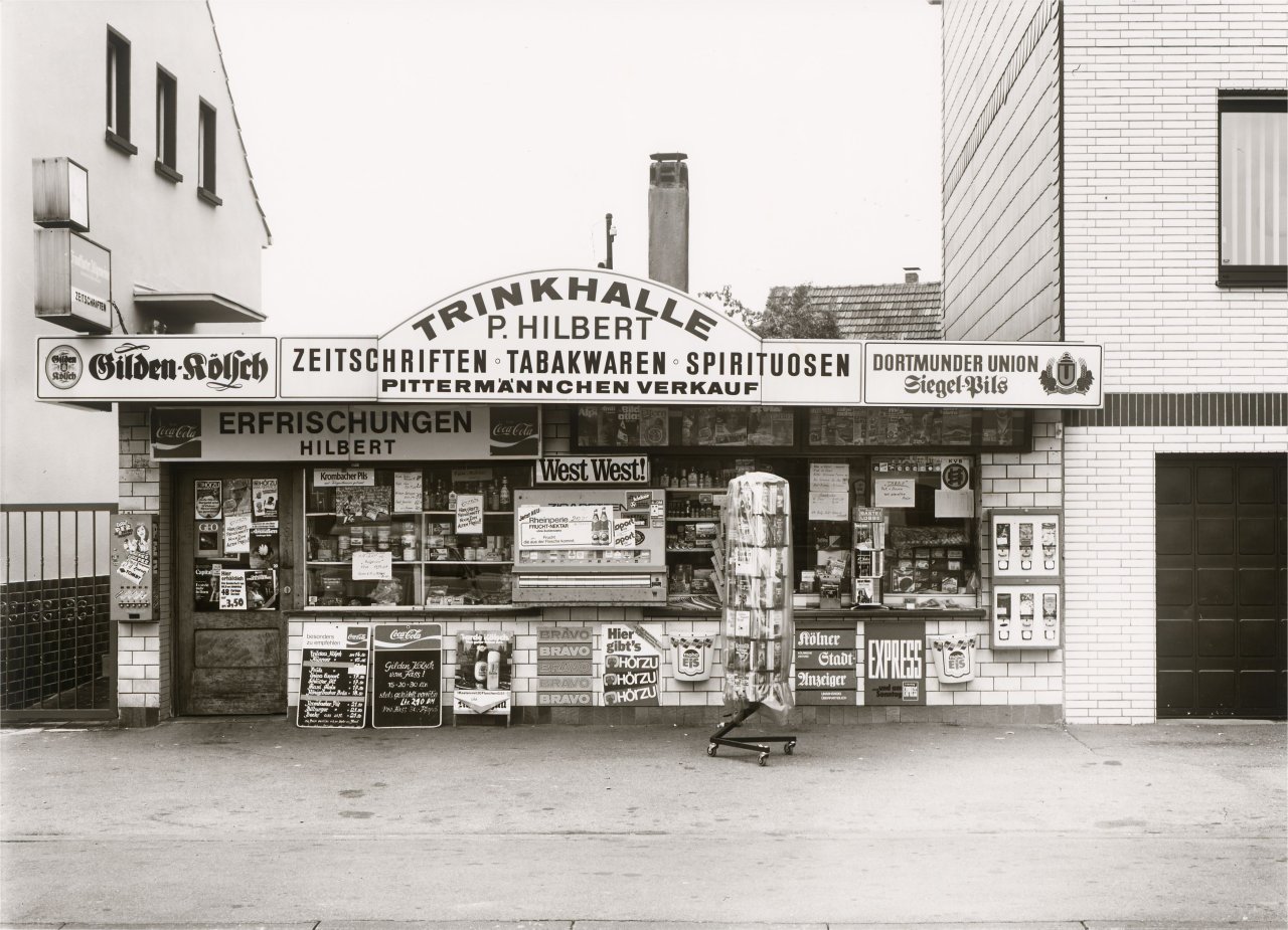 Auf diesem Bild ist das folgende Kunstwerk zu sehen: Tata Ronkholz. „Köln-Dünnwald, Odenthaler Straße 4“, aus der Serie „Trinkhallen“, 1977–1984. 1982.