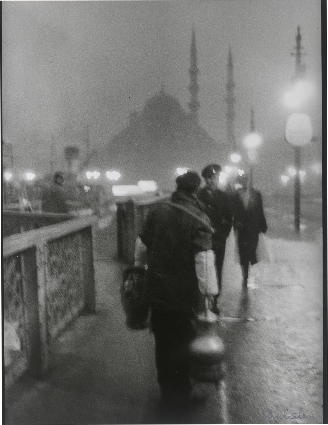 Auf diesem Bild ist das folgende Kunstwerk zu sehen: Ara Güler. 'Salep' Seller in early morning light on the old Galata Bridge. 1957.