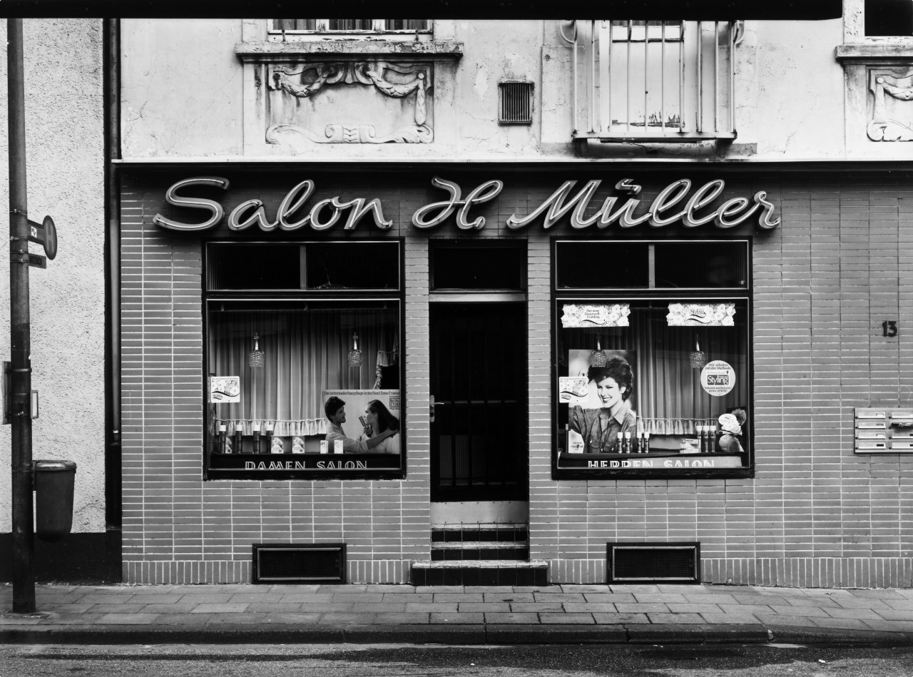 Auf diesem Bild ist das folgende Kunstwerk zu sehen: Tata Ronkholz. Köln-Mülheim, Berliner Strasse 913, aus der Serie „Läden“, 1978–1979. 1982.