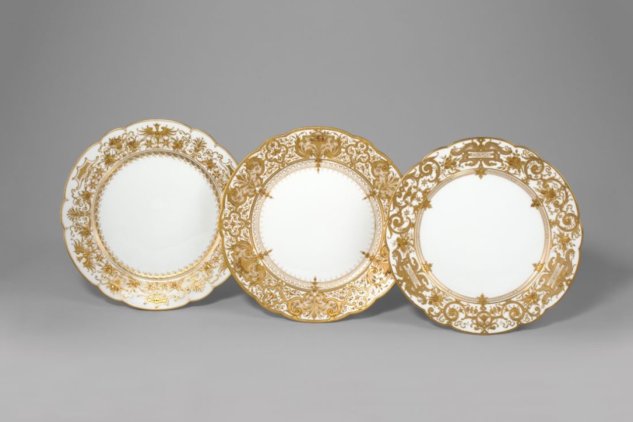 Auf diesem Bild ist das folgende Kunstwerk zu sehen:  KPM Königliche Porzellan-Manufaktur Berlin. Zierteller Augustaform mit Harpien und Fruchtkörben in Reliefgold. Um 1900/10.