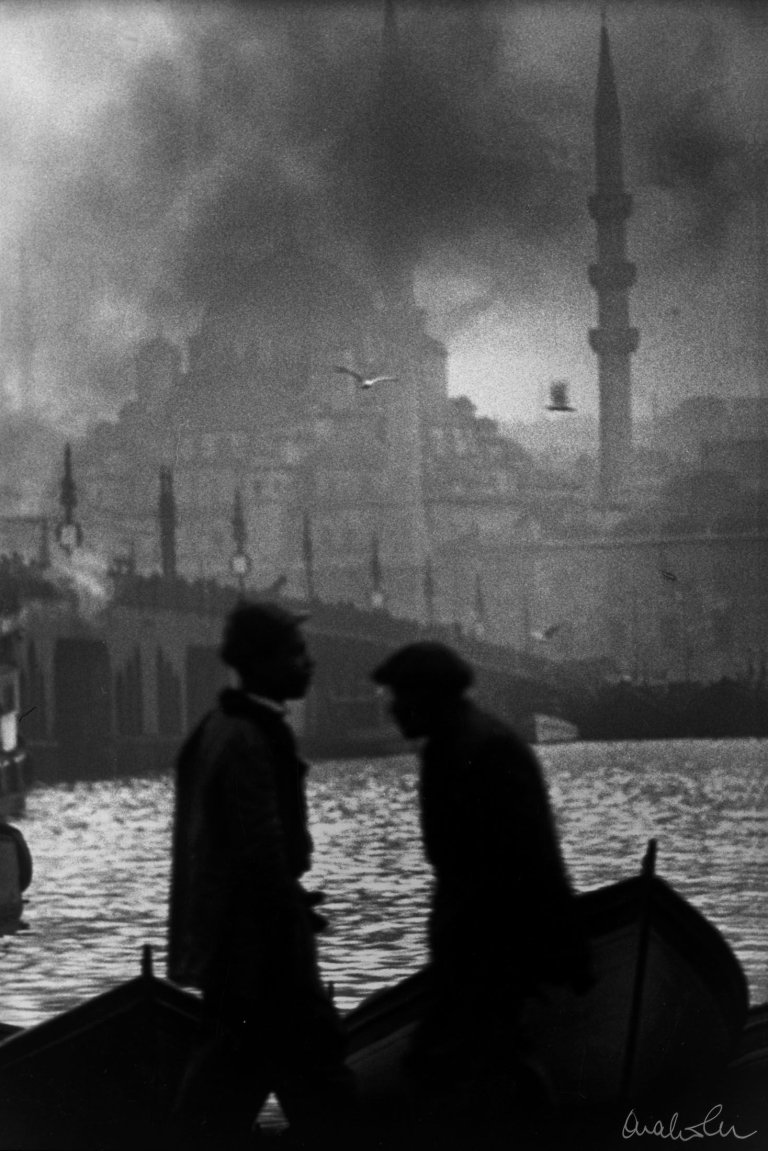 Auf diesem Bild ist das folgende Kunstwerk zu sehen: Ara Güler. Bootsleute am Goldenen Horn, die alte Galata-Brücke und die Neue Moschee. 1956.
