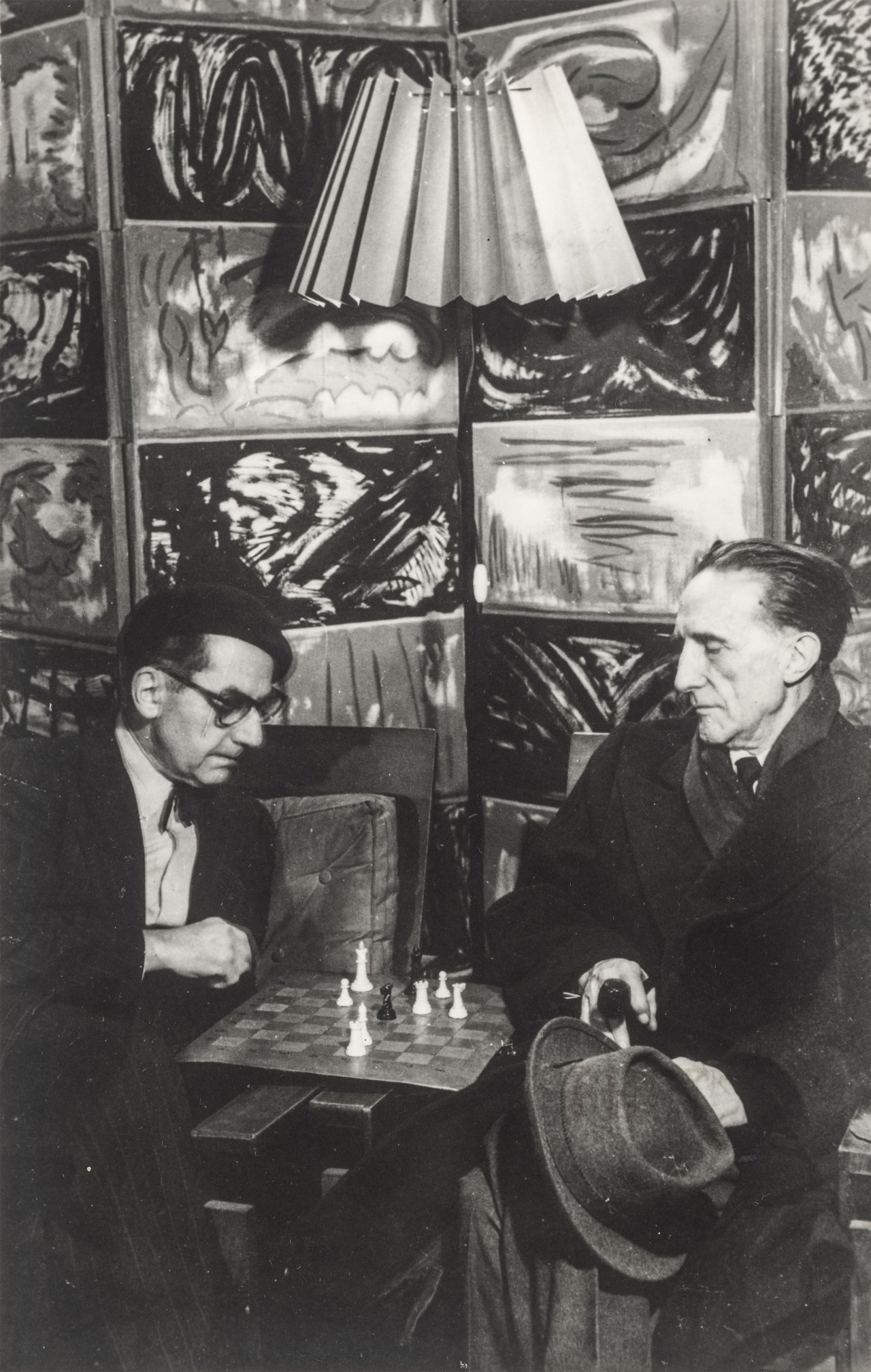 Auf diesem Bild ist das folgende Kunstwerk zu sehen:  Man Ray. Man Ray und Marcel Duchamp beim Schach in Man Rays Atelier in der Rue Férou, Paris. 1952/1960.