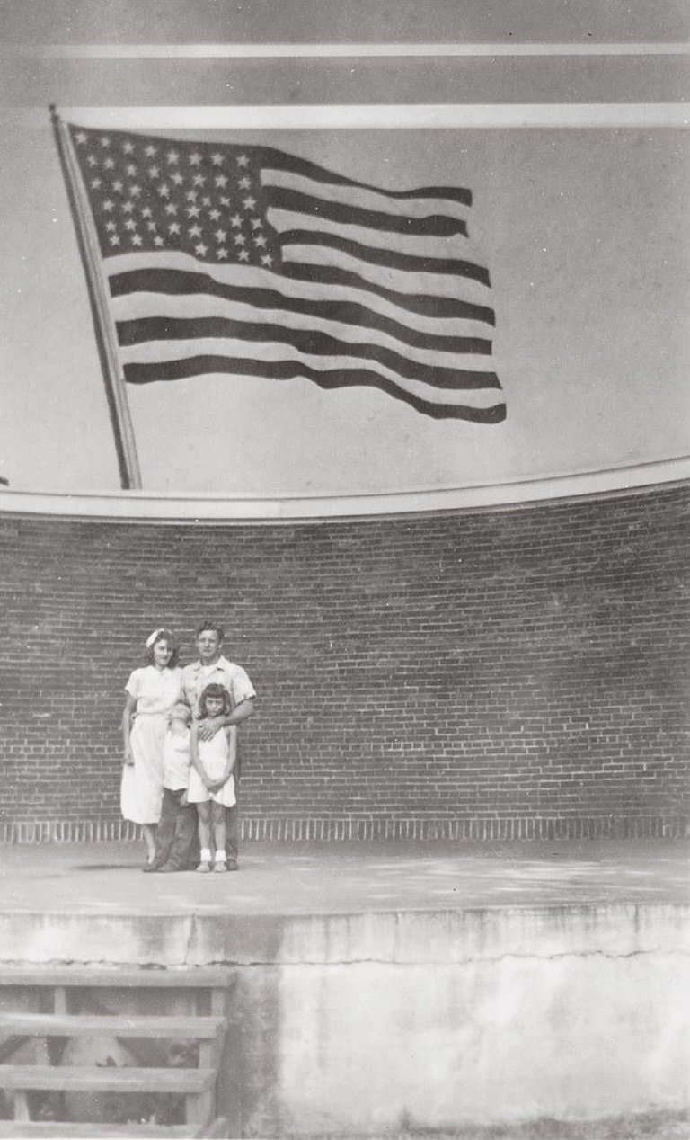 Auf diesem Bild ist das folgende Kunstwerk zu sehen:  Anonym. Ohne Titel (Familie vor amerikanischer Flagge). 1930er–1940er Jahre.