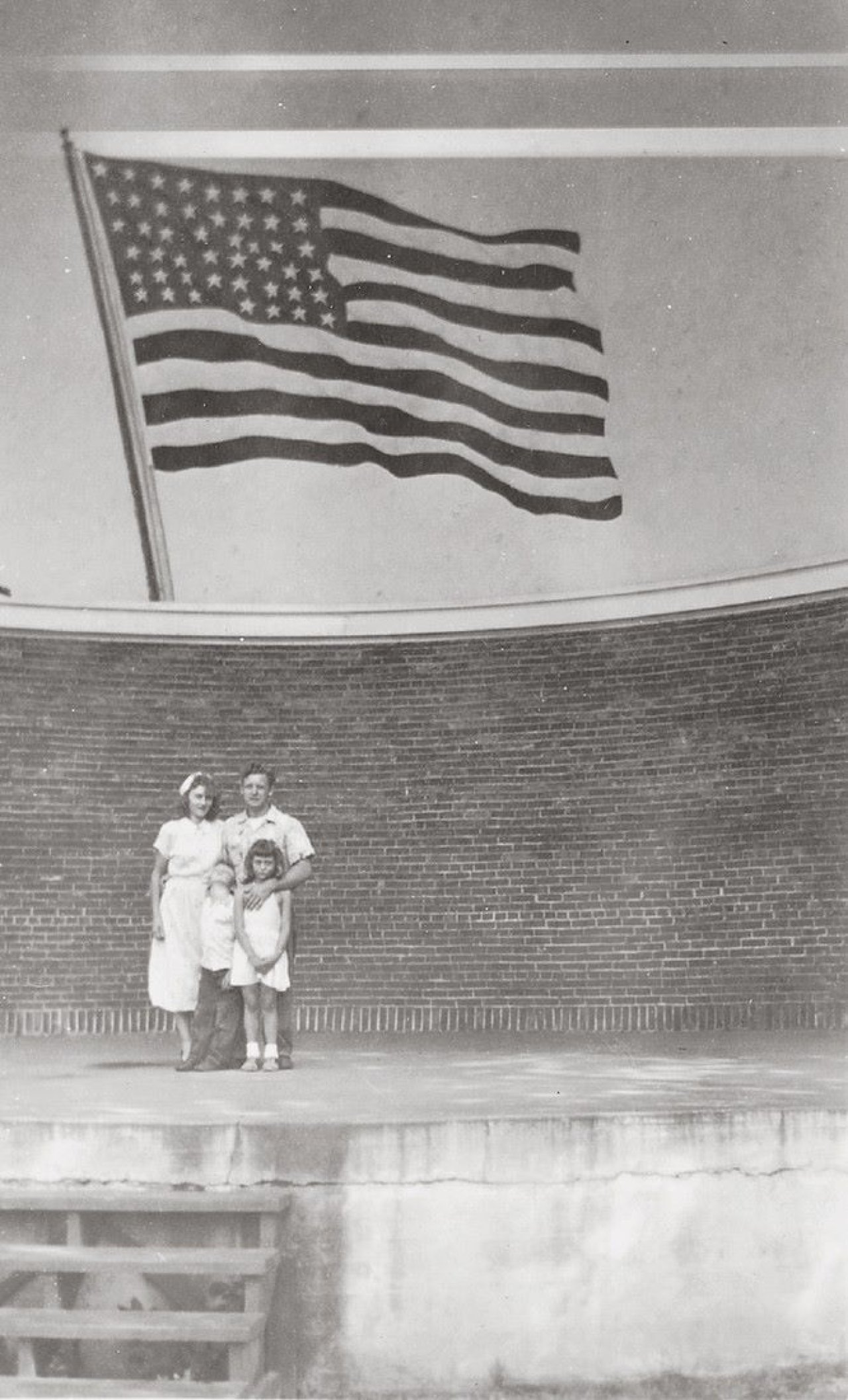 Auf diesem Bild ist das folgende Kunstwerk zu sehen:  Anonym. Ohne Titel (Familie vor amerikanischer Flagge). 1930er–1940er Jahre.