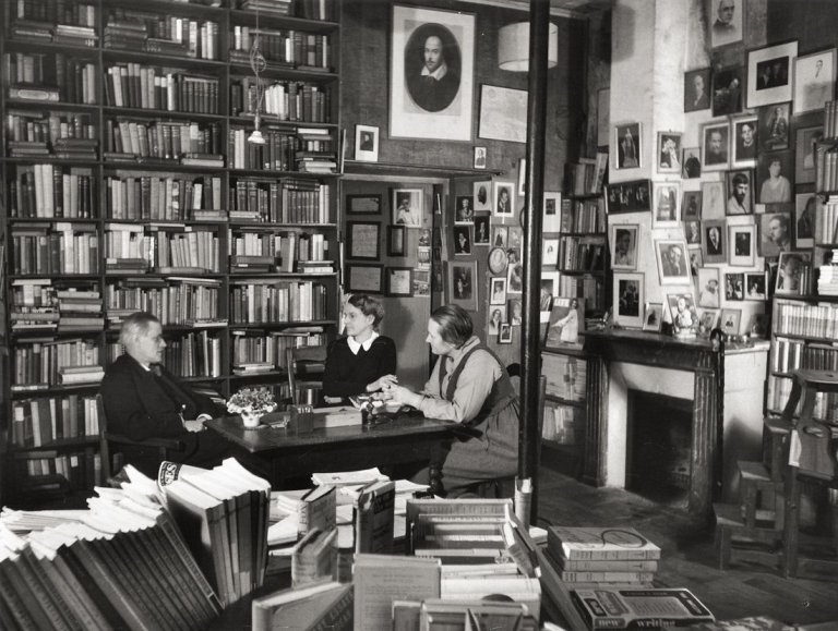 Auf diesem Bild ist das folgende Kunstwerk zu sehen: Gisèle Freund. James Joyce mit Adrienne Monnier und Sylvia Beach in der Buchhandlung Shakespeare & Co., Paris. 1938.