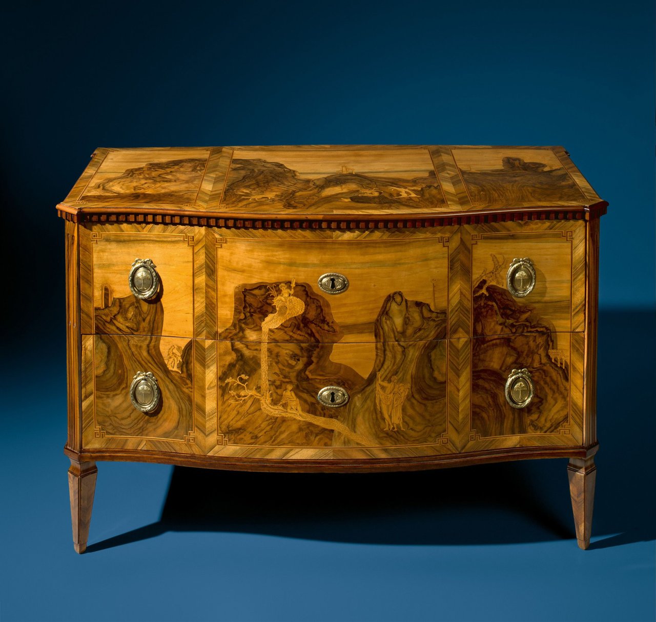 Auf diesem Bild ist das folgende Kunstwerk zu sehen: Werkstatt der Gebrüder Spindler. Kommode mit phantastischer Landschaft in Marketerie für den Bayreuther Hof. Um 1765.