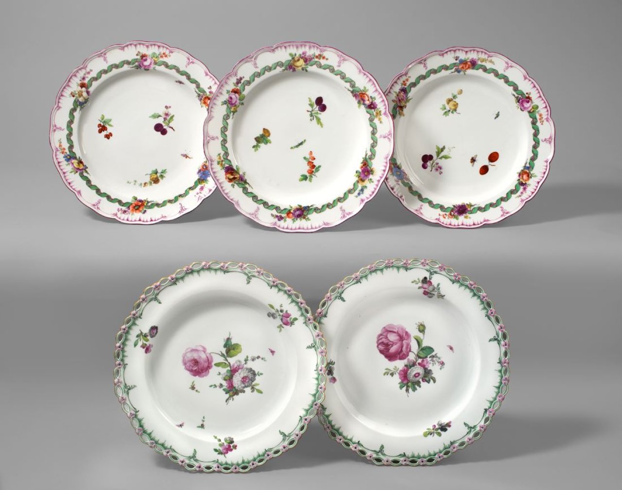 Auf diesem Bild ist das folgende Kunstwerk zu sehen:  KPM Königliche Porzellan-Manufaktur Berlin. Drei Teller Neuglatt mit grünem Spiralband um gestreiften Purpurring mit Blumen- und Früchtemalerei. Um 1780/85.