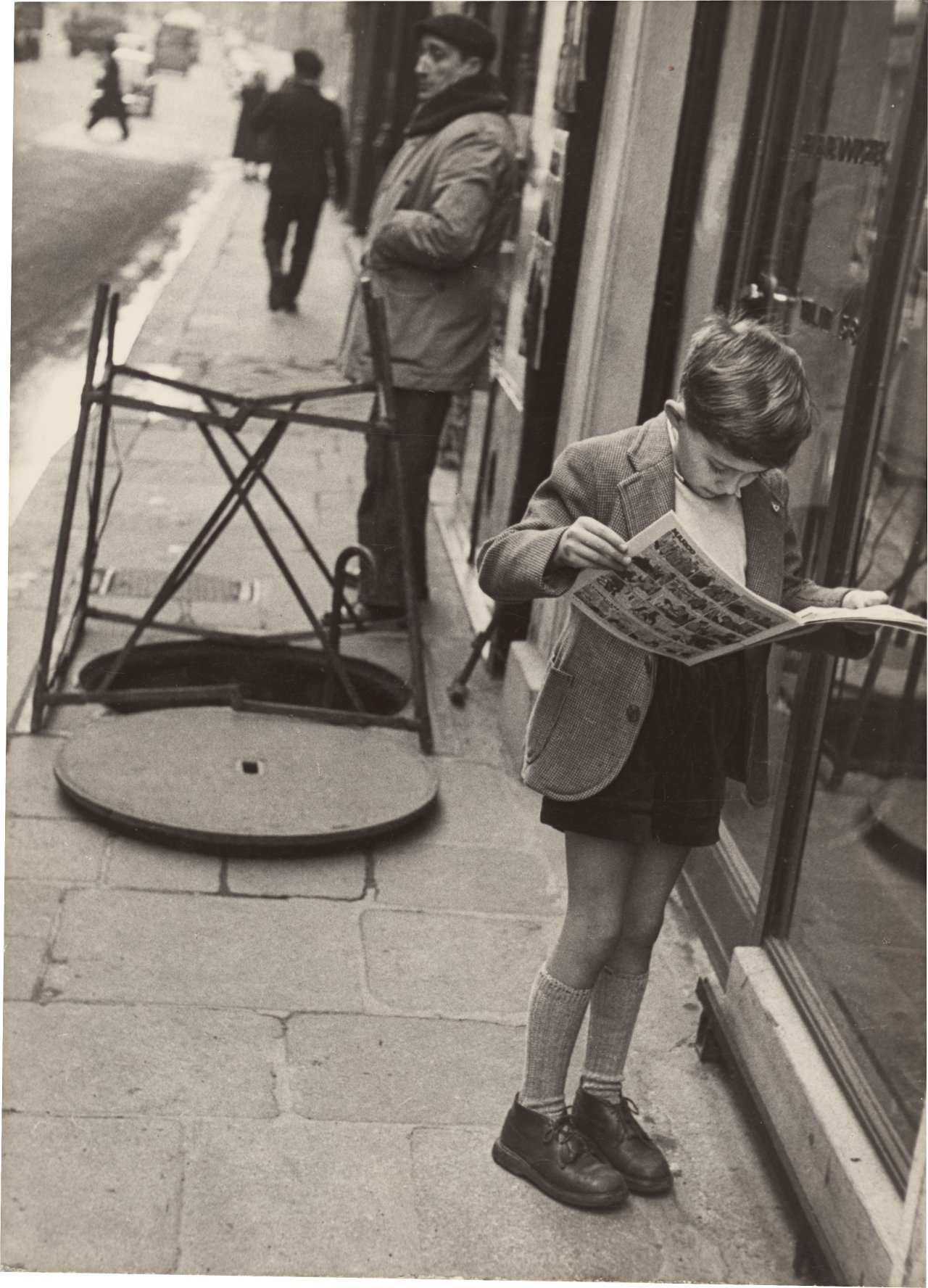 Auf diesem Bild ist das folgende Kunstwerk zu sehen: Louis Stettner. „Boy reading Comics, Paris“. 1951.