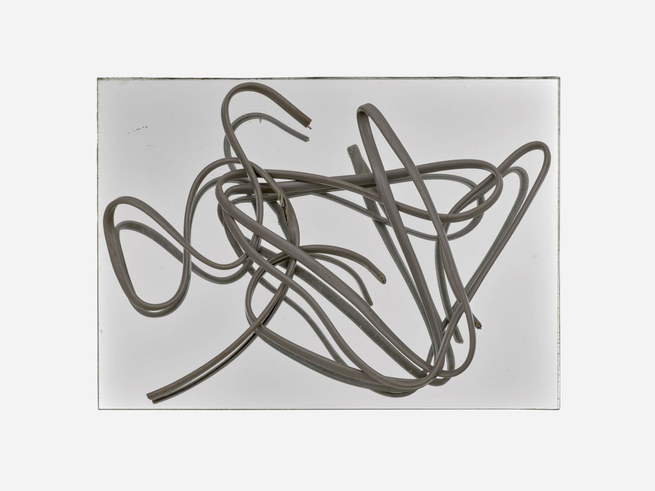 Auf diesem Bild ist das folgende Kunstwerk zu sehen: Hermann Glöckner. Grau ummanteltes, dreiadriges Aluminiumkabel auf Spiegel.