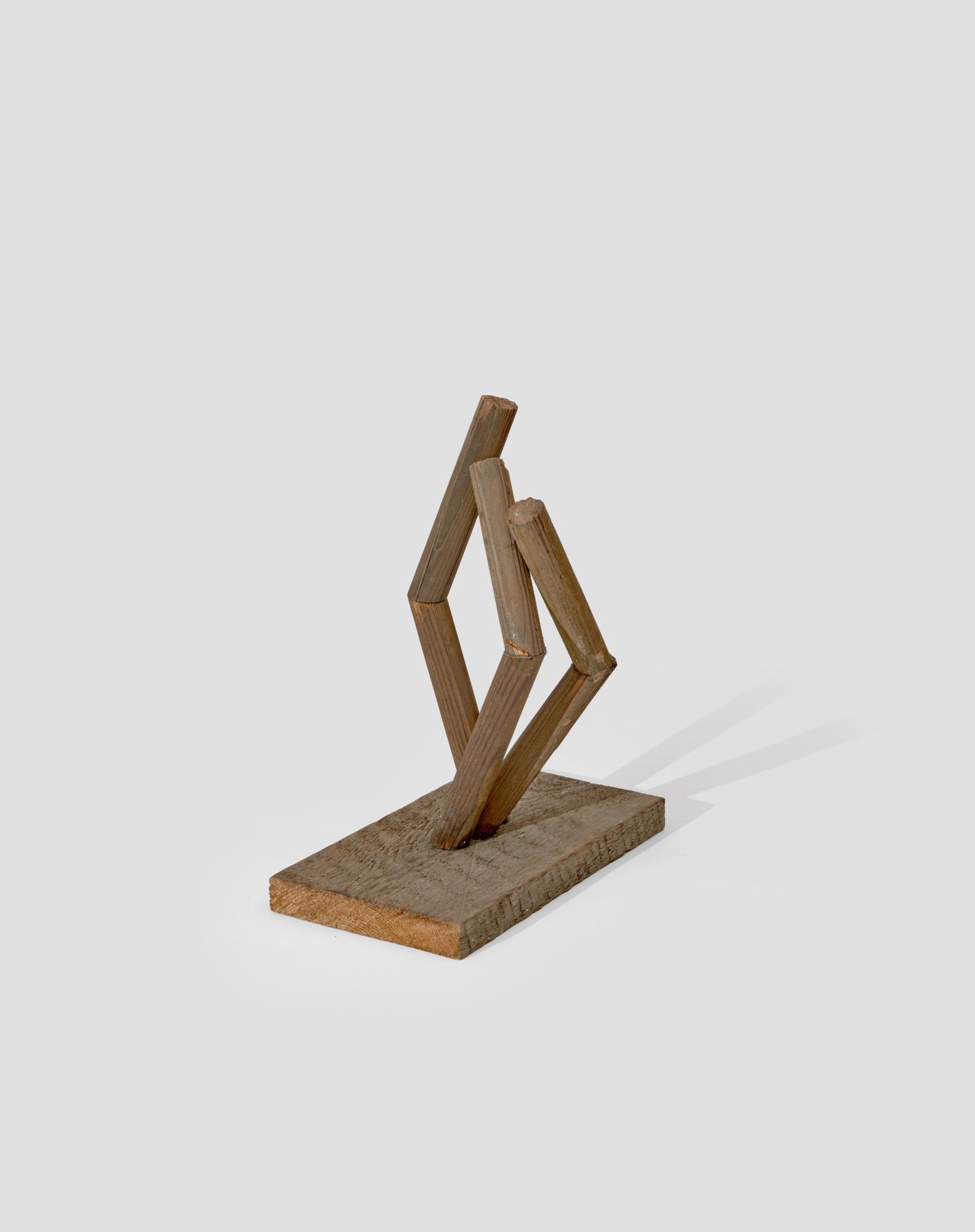 Auf diesem Bild ist das folgende Kunstwerk zu sehen: Hermann Glöckner. Aufrichtung von drei geteilten und gewinkelten Rundhölzern auf Holzplinthe. 1978.
