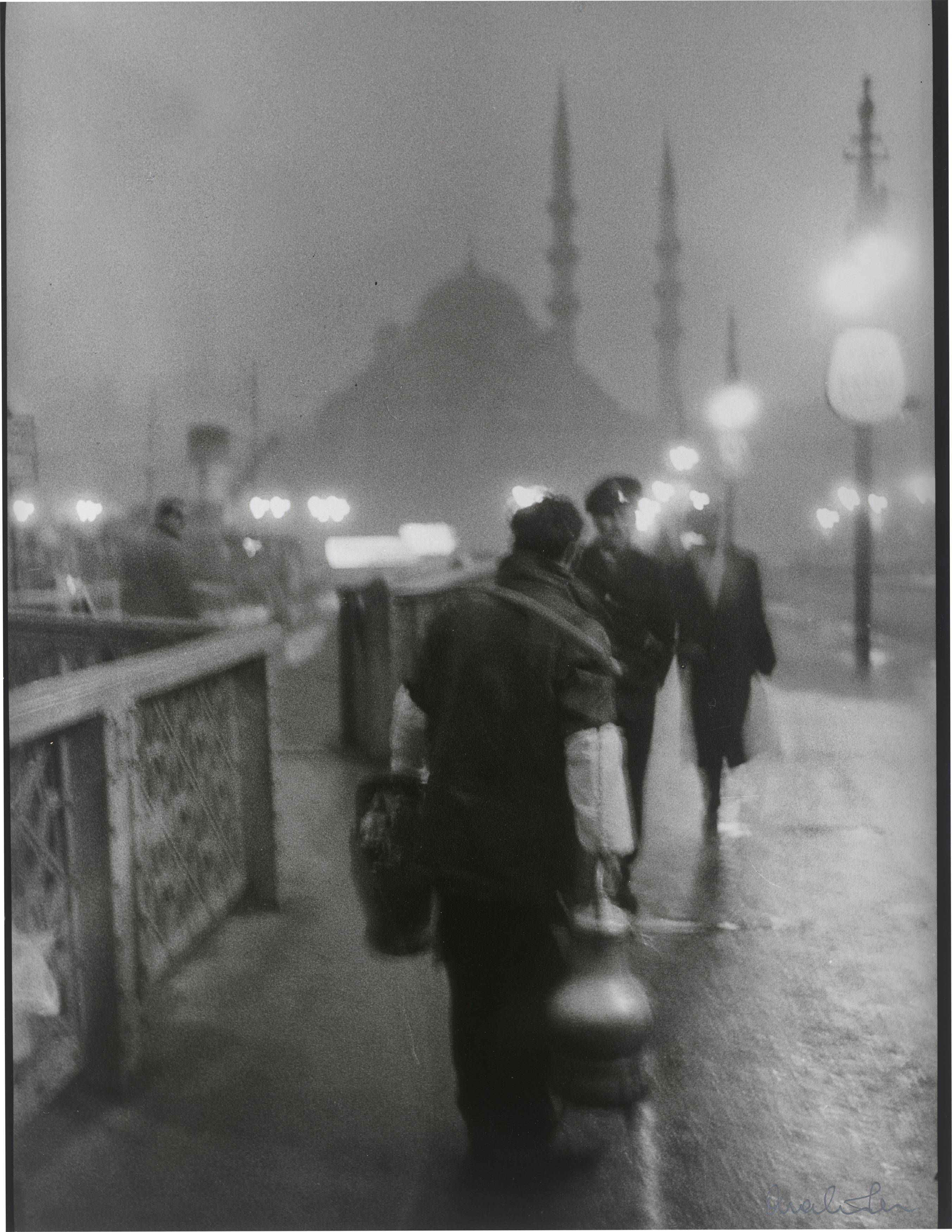 This picture shows the following artwork: Ara Güler. 'Salep' Seller in early morning light on the old Galata Bridge. 1957.