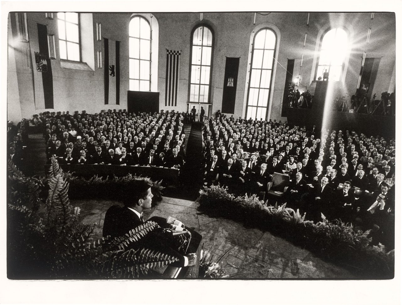 Auf diesem Bild ist das folgende Kunstwerk zu sehen: Will McBride. „John F. Kennedy spricht in der Paulskirche, Frankfurt am Main“. 1963.