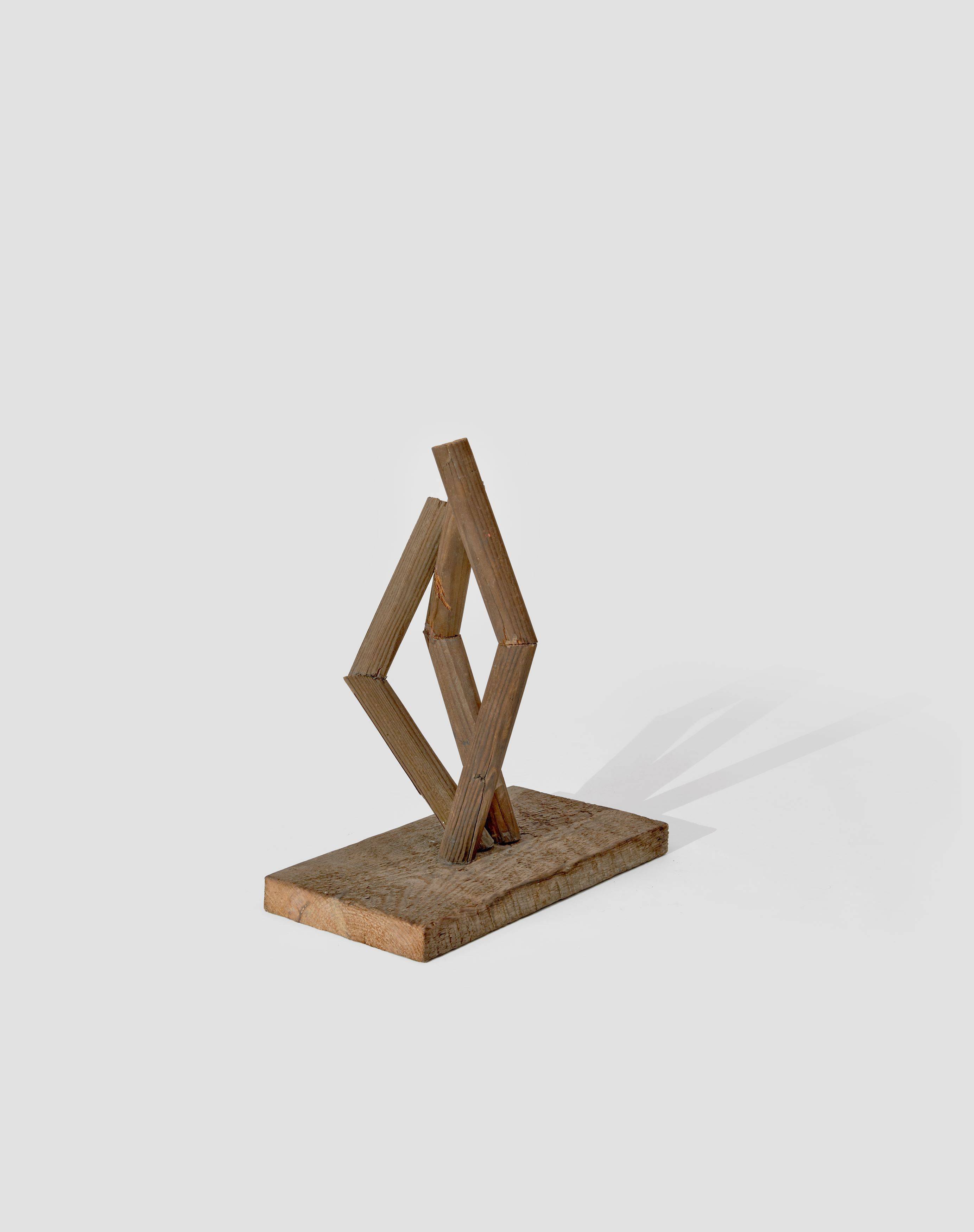 Auf diesem Bild ist das folgende Kunstwerk zu sehen: Hermann Glöckner. Aufrichtung von drei geteilten und gewinkelten Rundhölzern auf Holzplinthe. 1978.