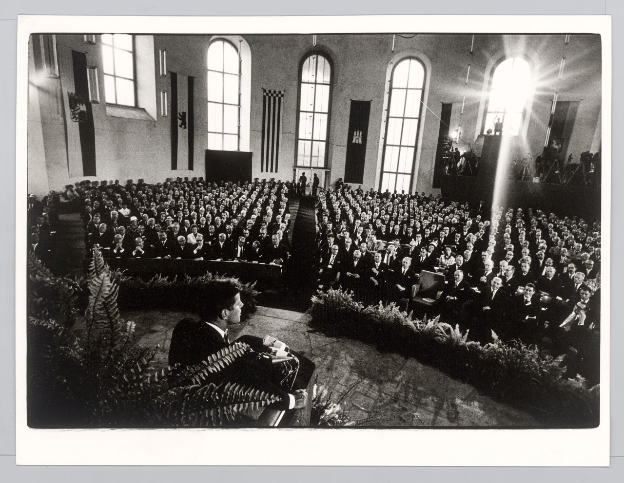 Auf diesem Bild ist das folgende Kunstwerk zu sehen: Will McBride. „John F. Kennedy spricht in der Paulskirche, Frankfurt am Main“. 1963.