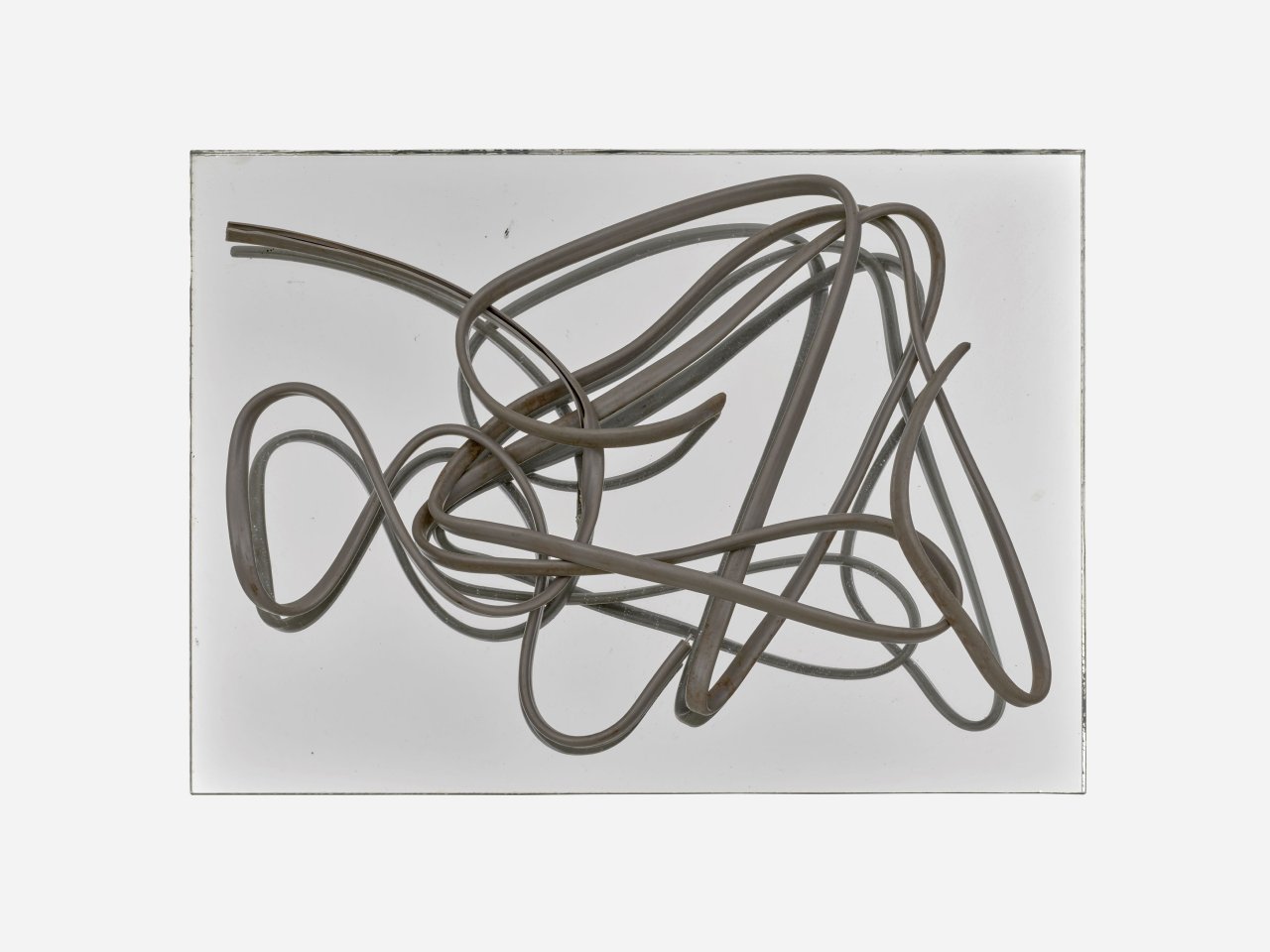 Auf diesem Bild ist das folgende Kunstwerk zu sehen: Hermann Glöckner. Grau ummanteltes, dreiadriges Aluminiumkabel auf Spiegel.