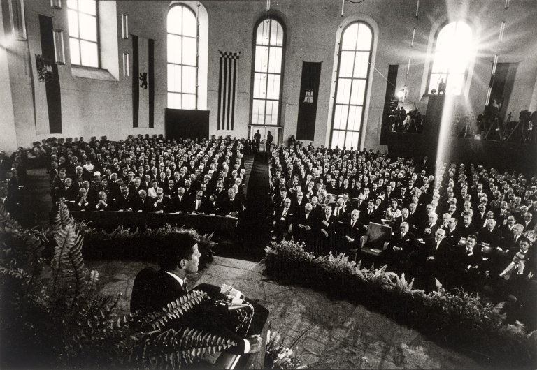 Auf diesem Bild ist das folgende Kunstwerk zu sehen: Will McBride. „John F. Kennedy spricht in der Paulskirche, Frankfurt am Main“. 1963.