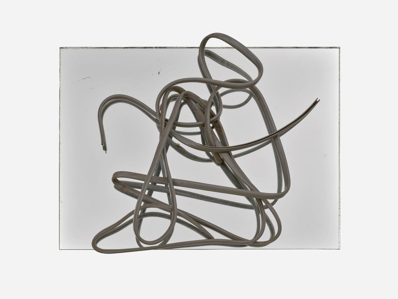 Auf diesem Bild ist das folgende Kunstwerk zu sehen: Hermann Glöckner. Grau ummanteltes, dreiadriges Aluminiumkabel auf Spiegel.